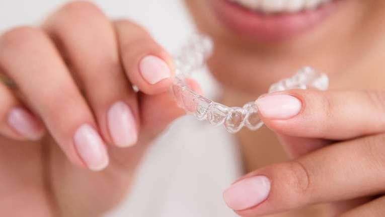 patient holding clear plastic aligner | invisalign 11201