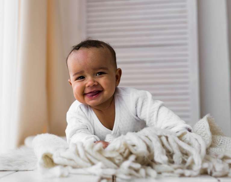 baby smiling with blanket | pediatric dentist dumbo