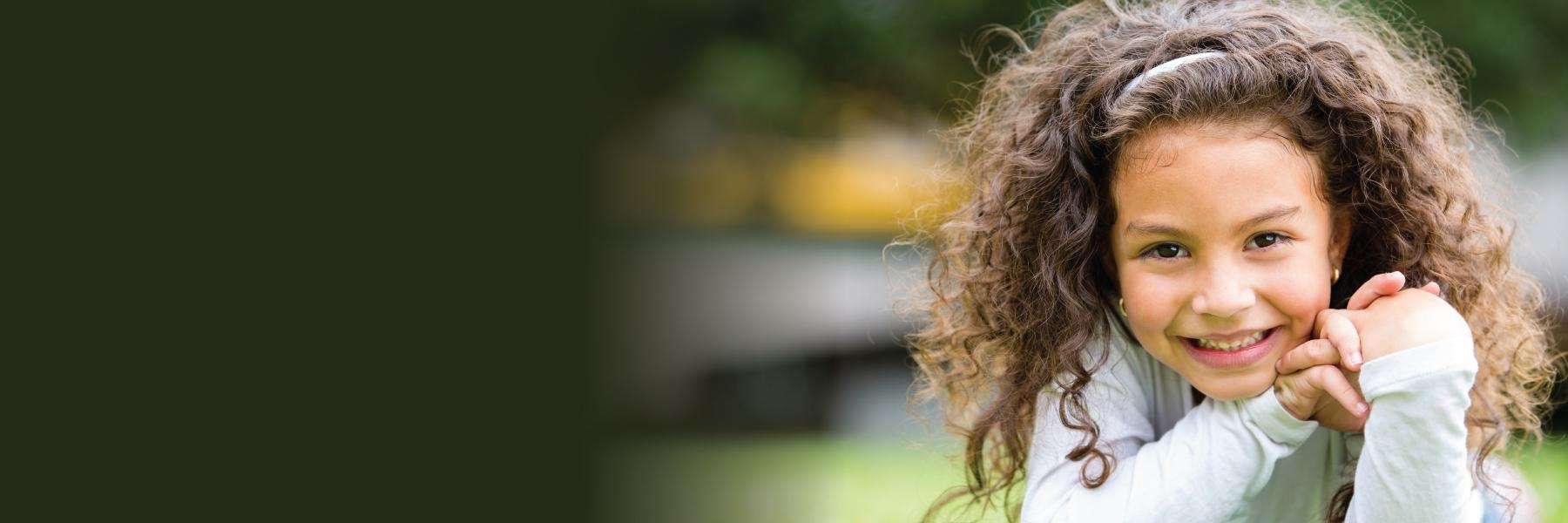 girl with curly hair smiling | pediatric dentist dumbo